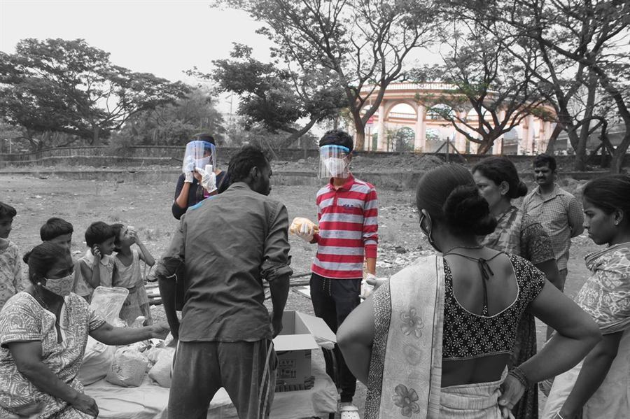 Volunteers in masks and face shields handing out supplies to families