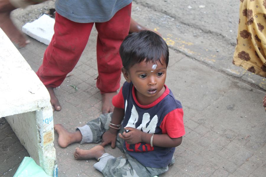 A small child sitting on a roadside kerb